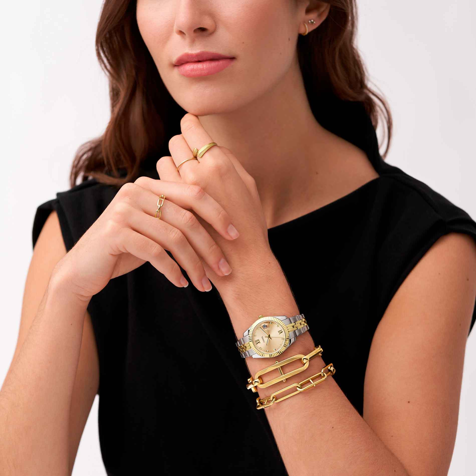 Fossil Scarlette Mini dameur i rustfrit stål med gyldne detaljer og gylden skive. Uret har datovisning. Uret ses på håndledet af en kvinde.