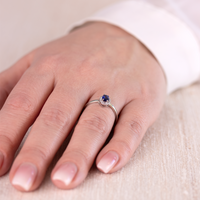 Forgyldt ring med en syntetisk blå safir omkranset af hvide zirkonia sten