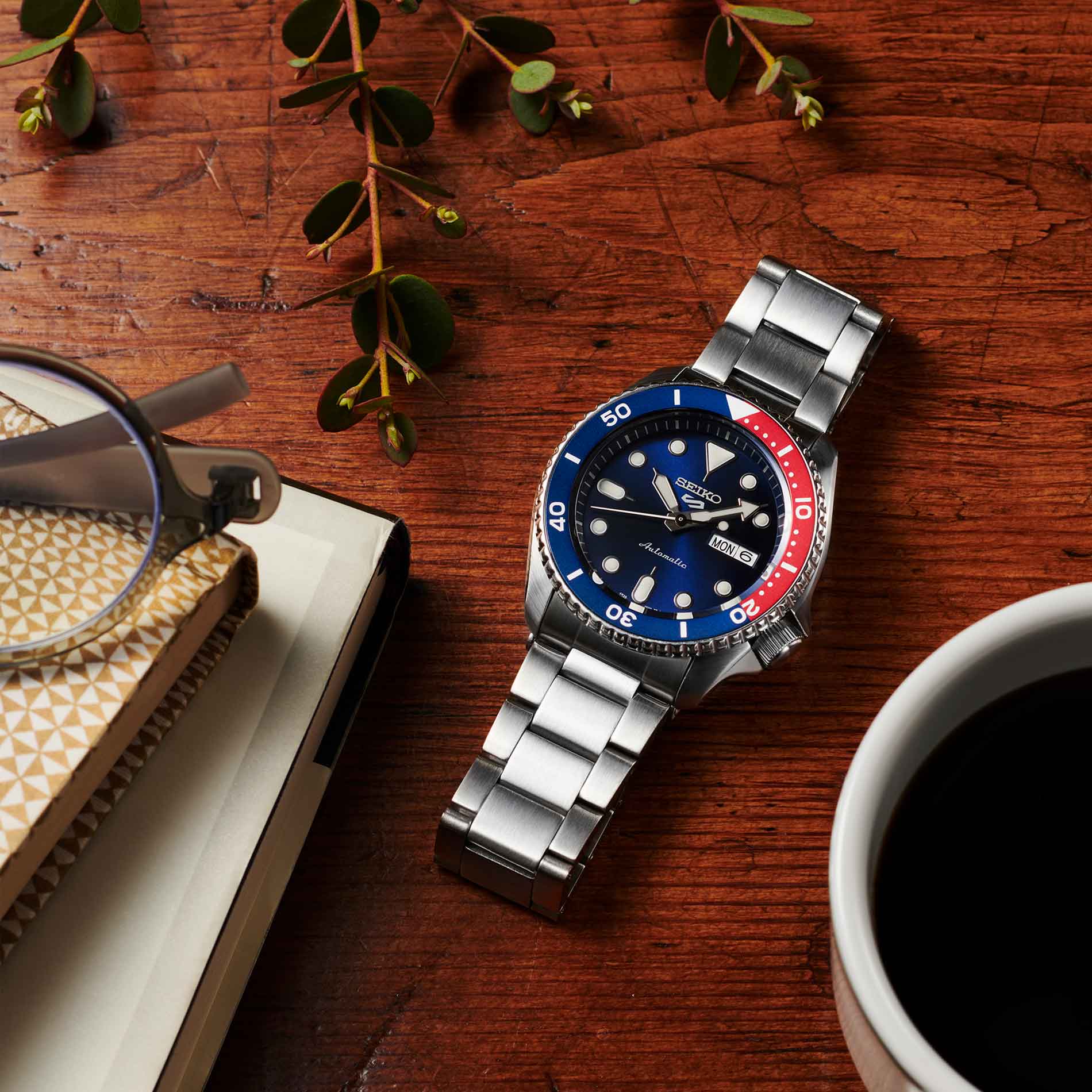 Seiko herreur i stål med blå urskive og blå / rød krans (Pepsi). Uret ses liggende på et bord.