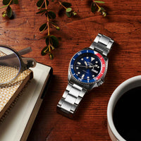 Seiko herreur i stål med blå urskive og blå / rød krans (Pepsi). Uret ses liggende på et bord.