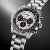 Seiko herreur i stål med hvid urskive med tre sorte chronographer. Uret har også sort urkrans. Uret ses skråt forfra med åben lænke på sort baggrund.