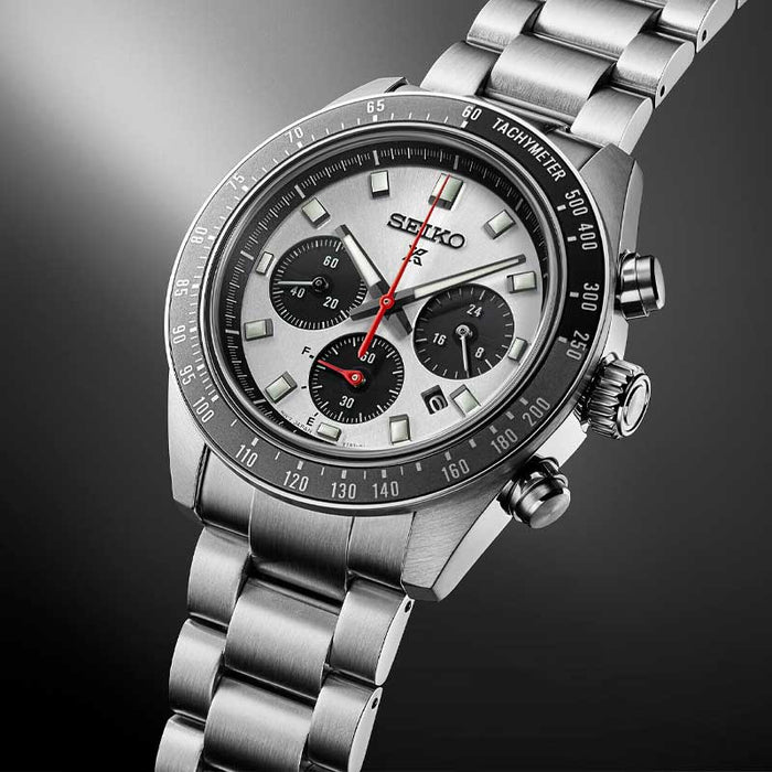 Seiko herreur i stål med hvid urskive med tre sorte chronographer. Uret har også sort urkrans. Uret ses skråt forfra med åben lænke på sort baggrund.