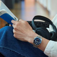 Seiko herreur i stål med blå urskive, hvide visere og indekseringer samt rød GMT-viser. Uret ses på et håndled.