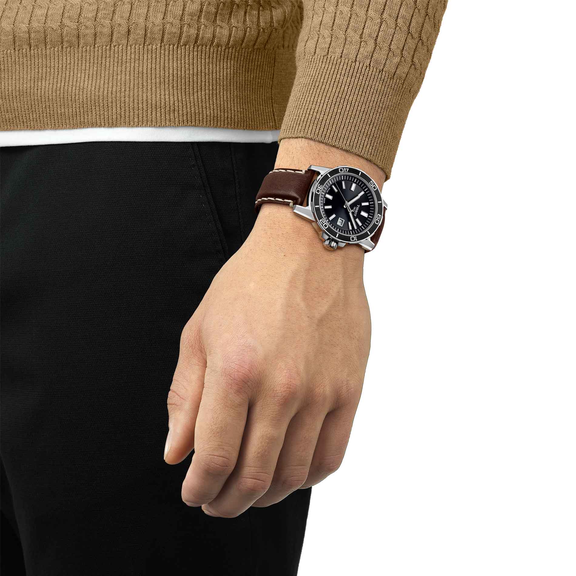 Herreur i stål med brun læderrem og sort skive fra tissot, på håndled