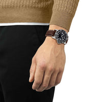 Herreur i stål med brun læderrem og sort skive fra tissot, på håndled