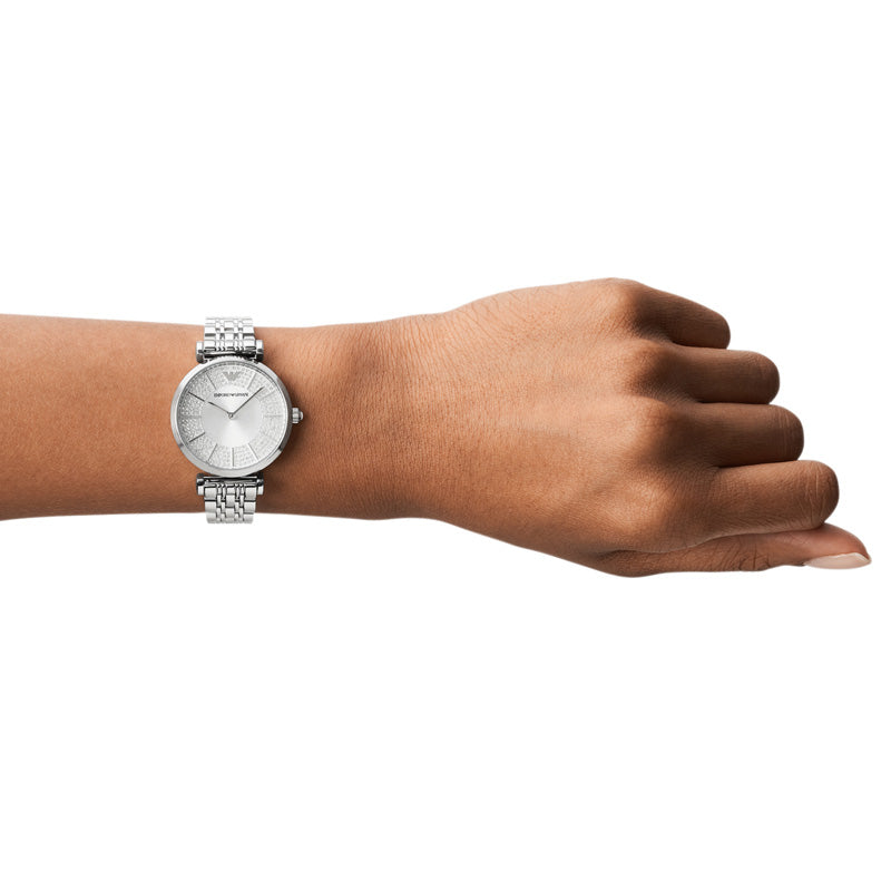 Emporio Armani Gianni T-Bar AR11445 dameur med stål-urkasse og sølvfarvet skive med romerske tal og glitrende krystaller. Uret ses på håndledet af en kvinde.