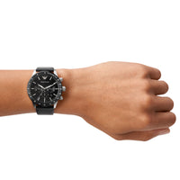 Emporio Armani Mario AR11243 herreur i stål med sort skive. Uret ses på håndledet af en mand.