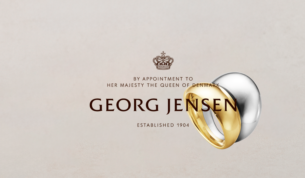 Georg Jensen logo med kongekronen og to Curve-ringe i guld og sølv – symbol på dansk design og håndværk
