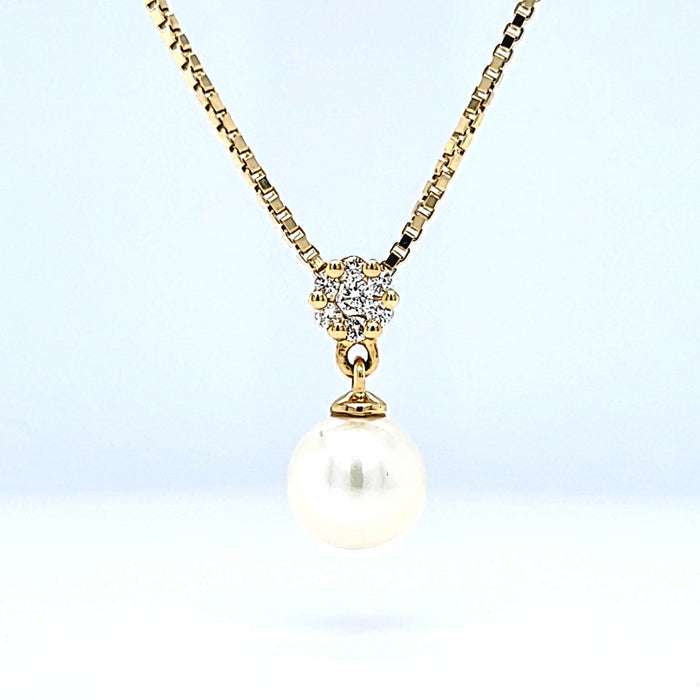 Vedhæng i guld med 7 diamanter formet som en blomst med en løs perle, set forfra på kæde