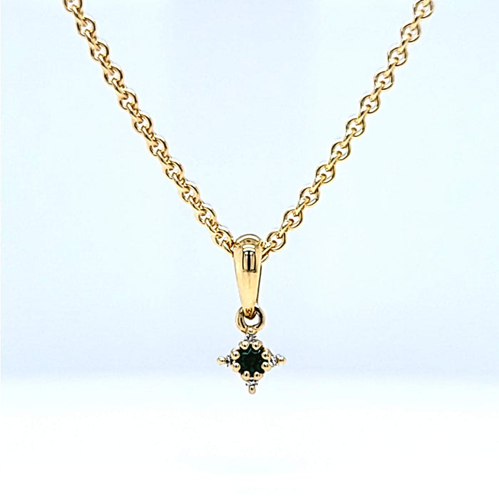 Vedhæng i guld med en grøn smaragd og fire hvide diamanter, set forfra på kæde