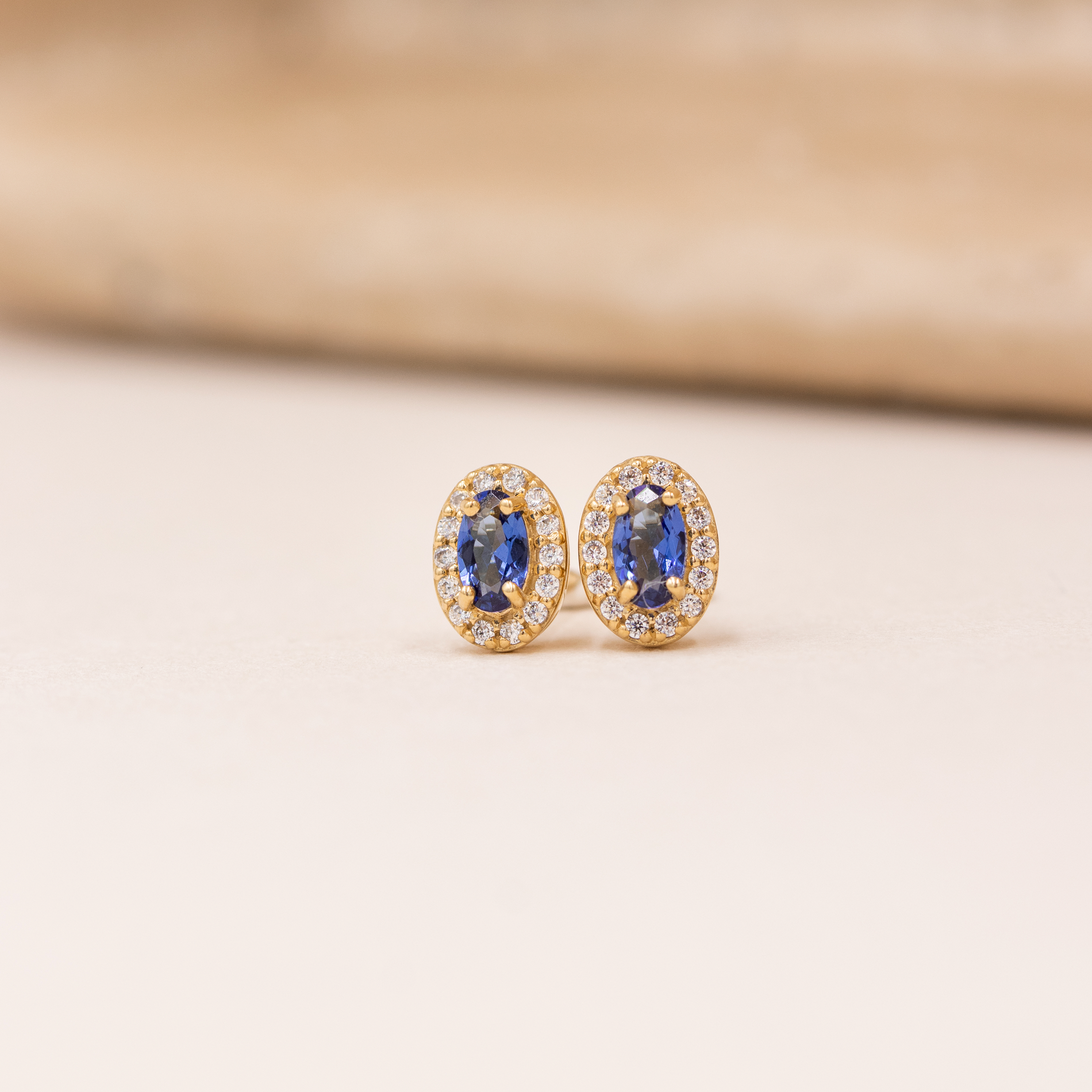 Elina ørestikker i forgyldt sølv med oval blå zirkonia omgivet af klare zirkonia