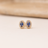 Elina ørestikker i forgyldt sølv med oval blå zirkonia omgivet af klare zirkonia