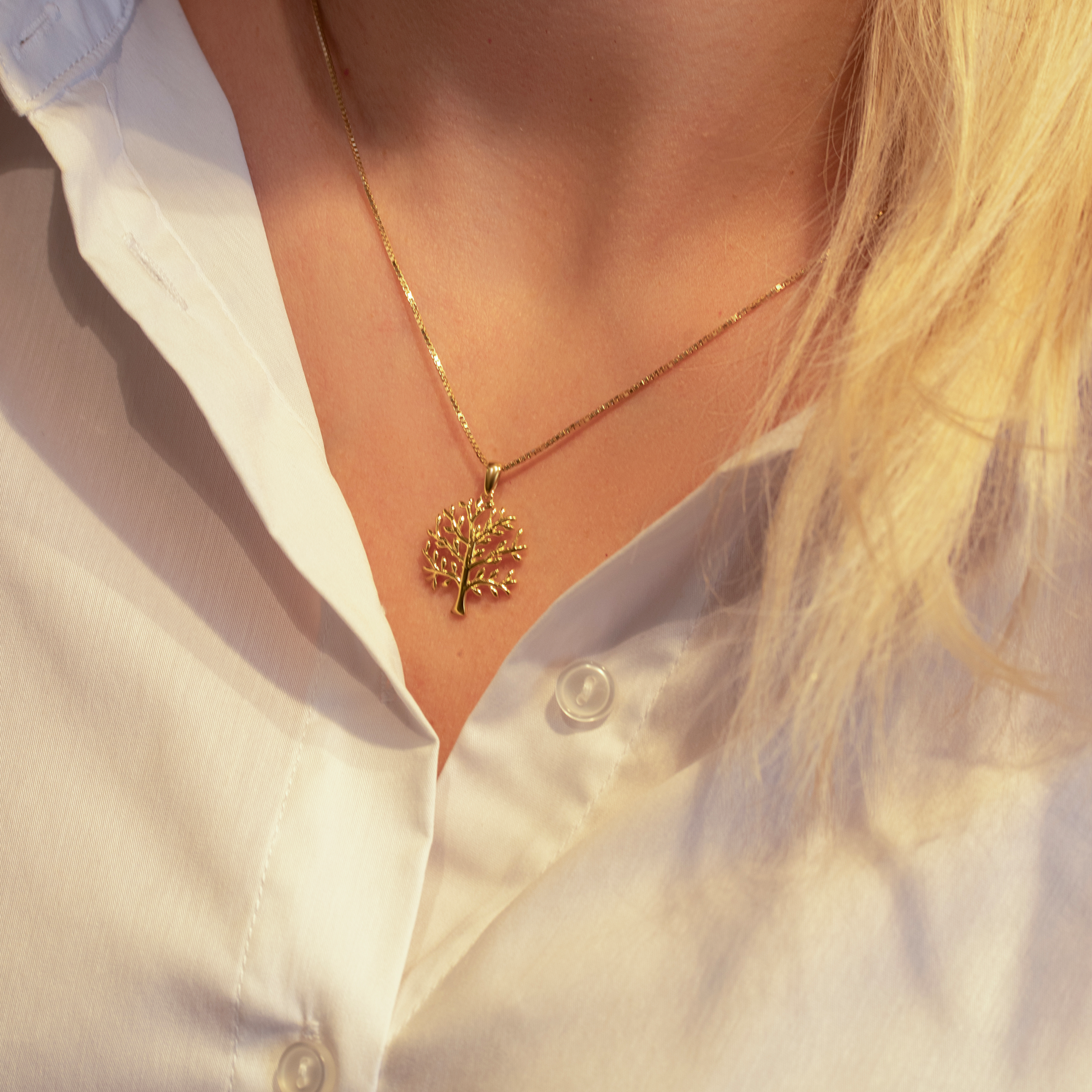 Leaf halskæde i forgyldt sølv båret på model med hvid skjorte.