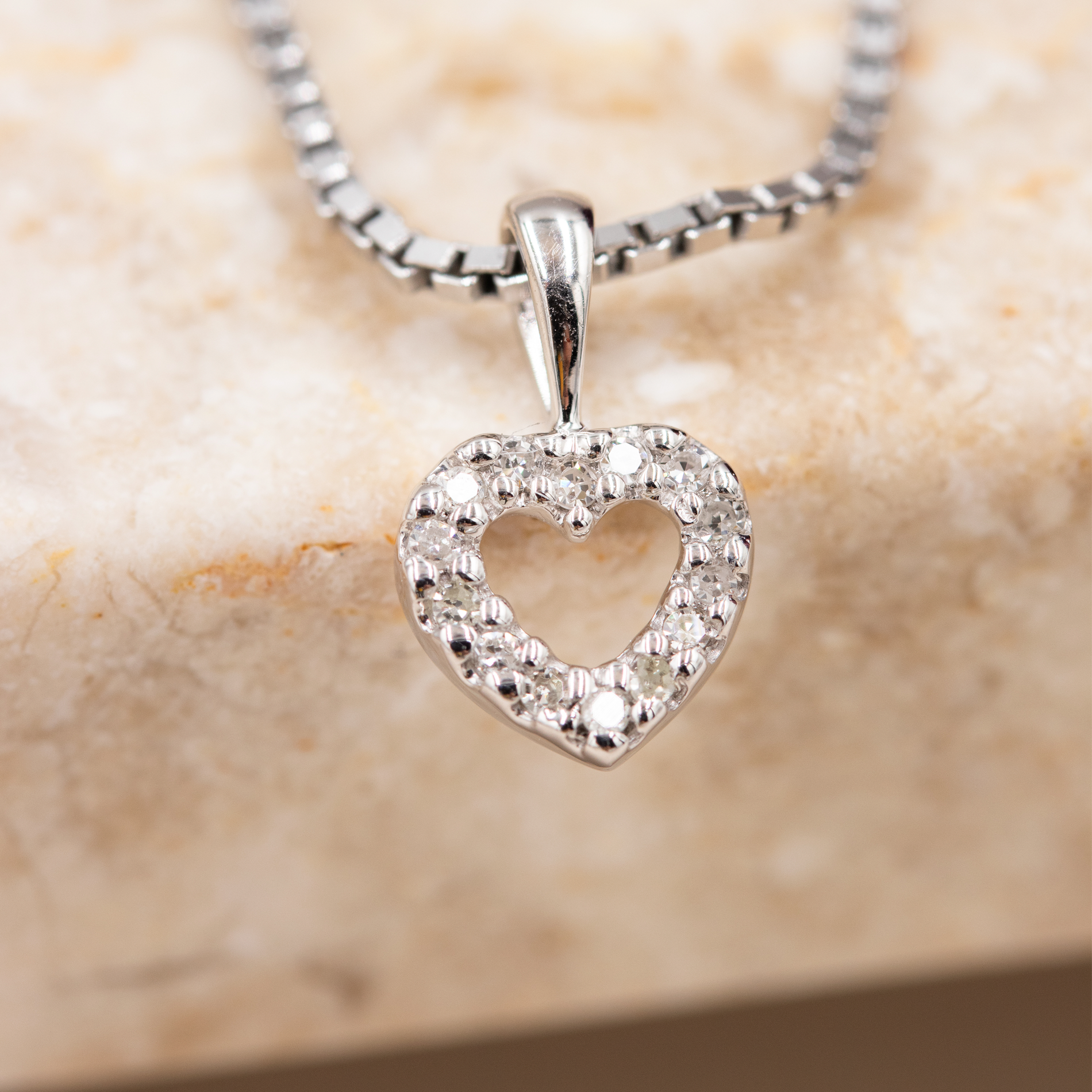 Nærbillede af diamantbesat hjerte vedhæng i hvidguld
