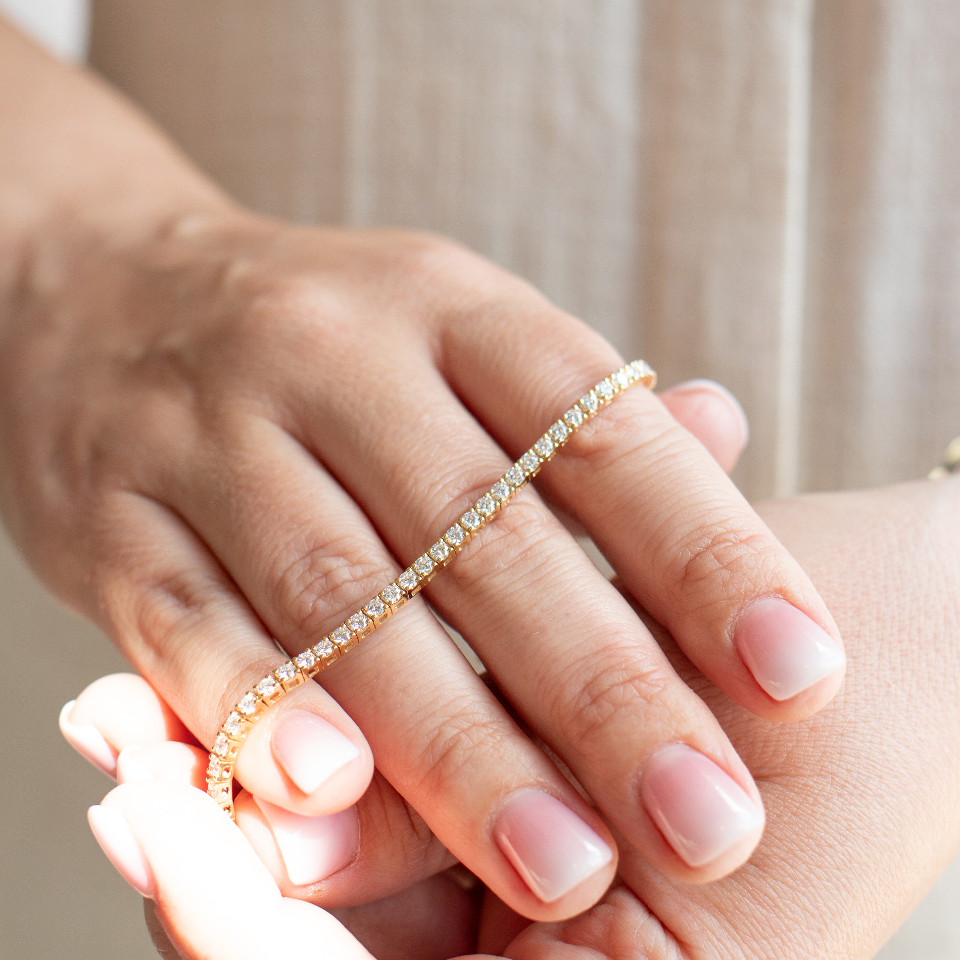 Tennisarmbånd i guld med en række diamanter i alt 2,78 carat, holdt ovenpå fingrene af model