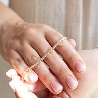 Tennisarmbånd i guld med en række diamanter i alt 2,78 carat, holdt ovenpå fingrene af model