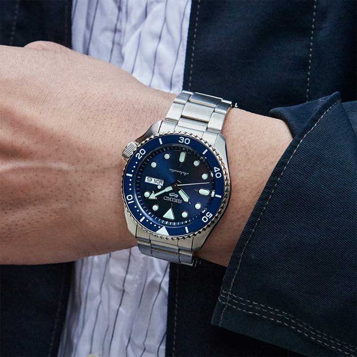 Seiko herreur i stål med blå urskive og dato. Uret ses på et håndled.