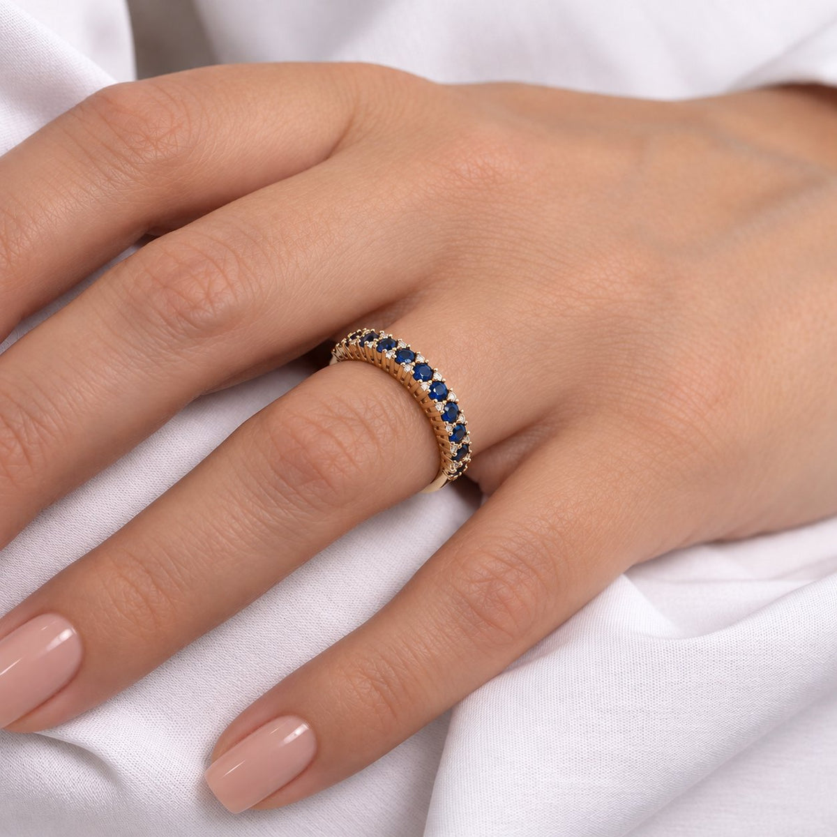 Kvinde bærer Adeline ring i guld med blå safirer