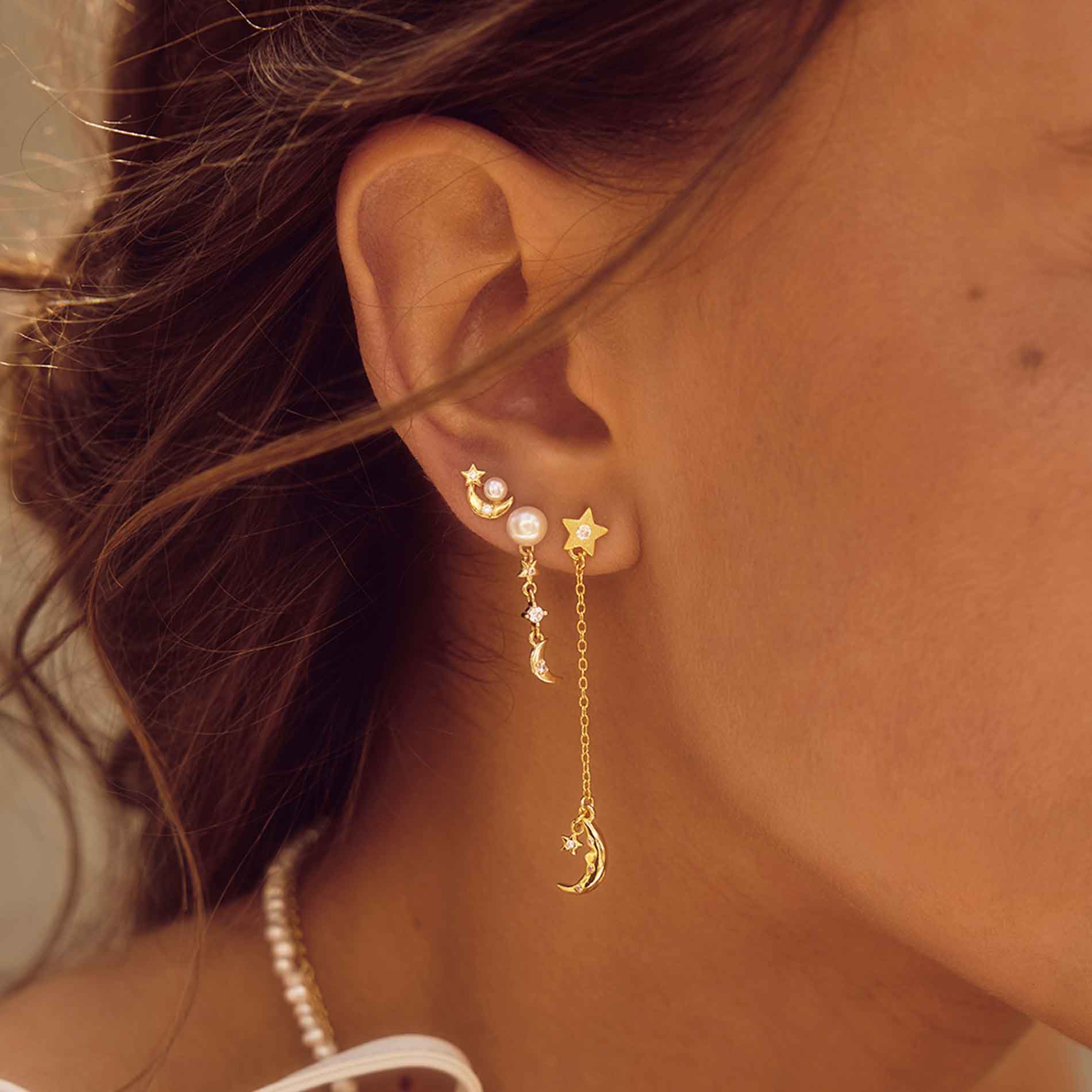 Aqua Dulce Dreamlit Long øreringe i forgyldt sølv med stjerne, måne og klar zirkonia båret på øret
