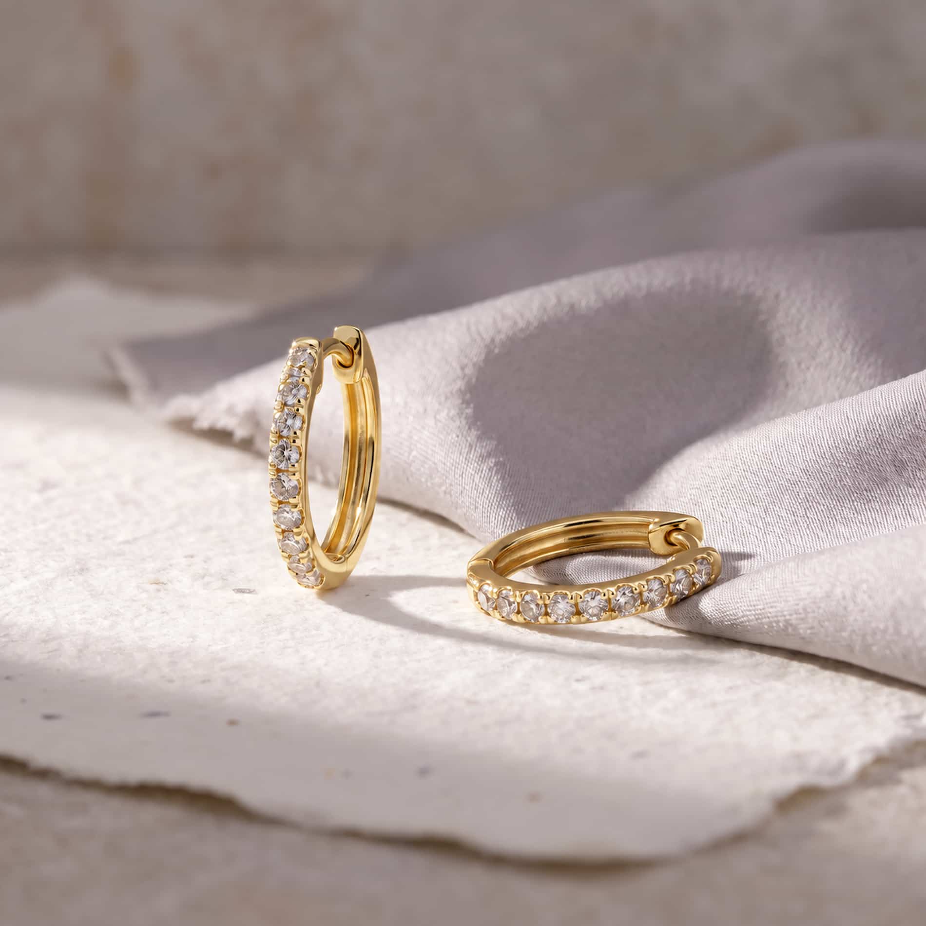 Diamond Hoops i 18 karat guld med 0,18 carat hvide diamanter, fotograferet på lyst stof