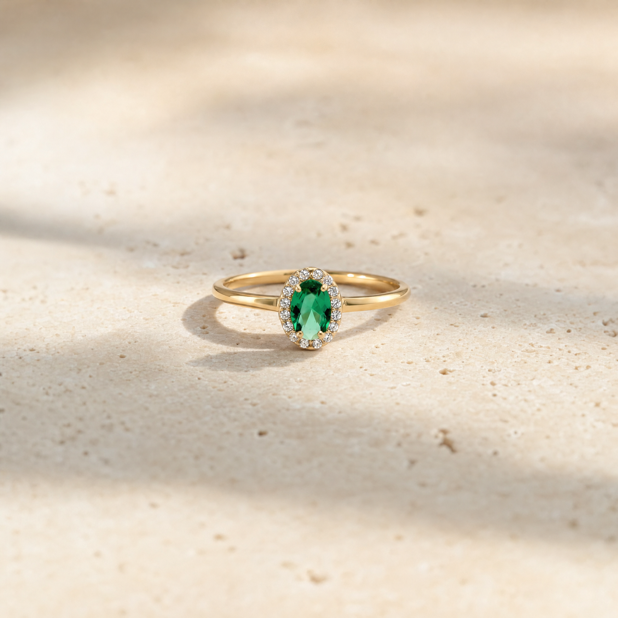 Elina Green roset ring i forgyldt sølv med grøn oval sten og zirkoner fotograferet på travertinsten