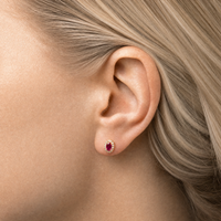 Modelbillede af Elina Ruby Roset ørestik i forgyldt sølv med rubinrød oval zirkonia omgivet af klare zirkonia. Den klassiske rosetørering bæres i øret og fremhæver et elegant og feminint udtryk.