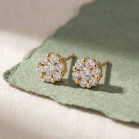 Fleur ørestikker i 18 karat guld med 0,16 carat hvide diamanter, vist på grønligt stof