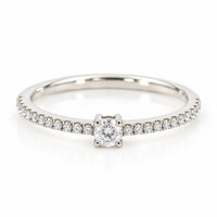 Infinity ring i 18 karat hvidguld med solitærdiamant og diamanter i skinnen, i alt 0,21 carat, hvid baggrund