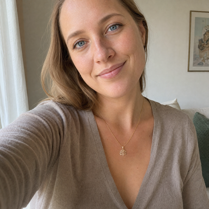 Kvinde bærer Livets Træ halskæde i 8 karat guld. Det elegante vedhæng med fine grene og blade symboliserer vækst, kærlighed og livets skønhed