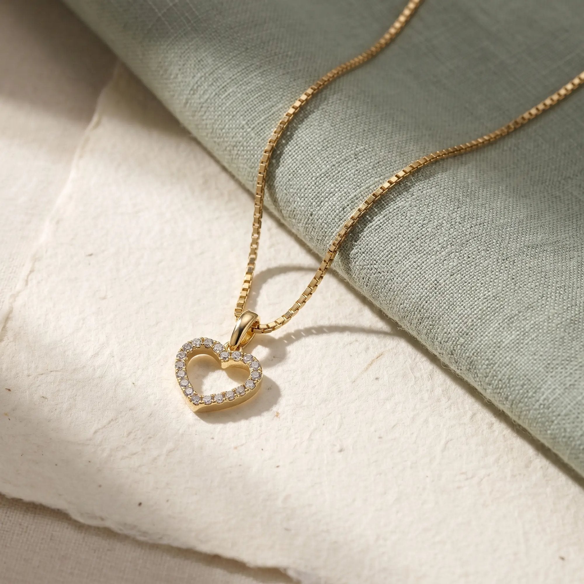 Lovely hjertevedhæng i guld med diamanter på grønt stof og papir