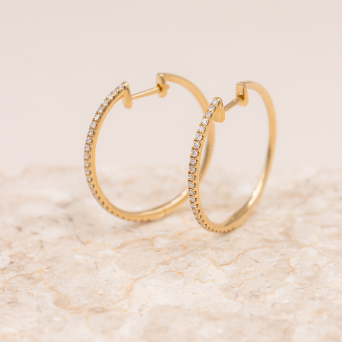 Lucie hoops i 18 kt. guld med diamanter på marmoroverflade
