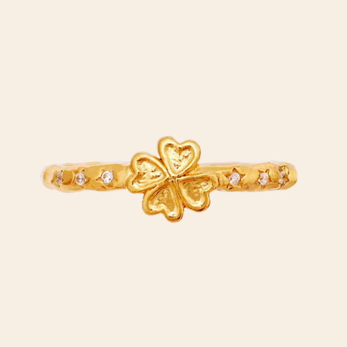 Maanesten Clover ring i forgyldt sølv set oppefra med dekorativt firkløvermotiv og små hvide zirkonia.