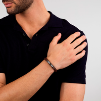 Maserati armbånd i brun læder båret af model med mørk polo