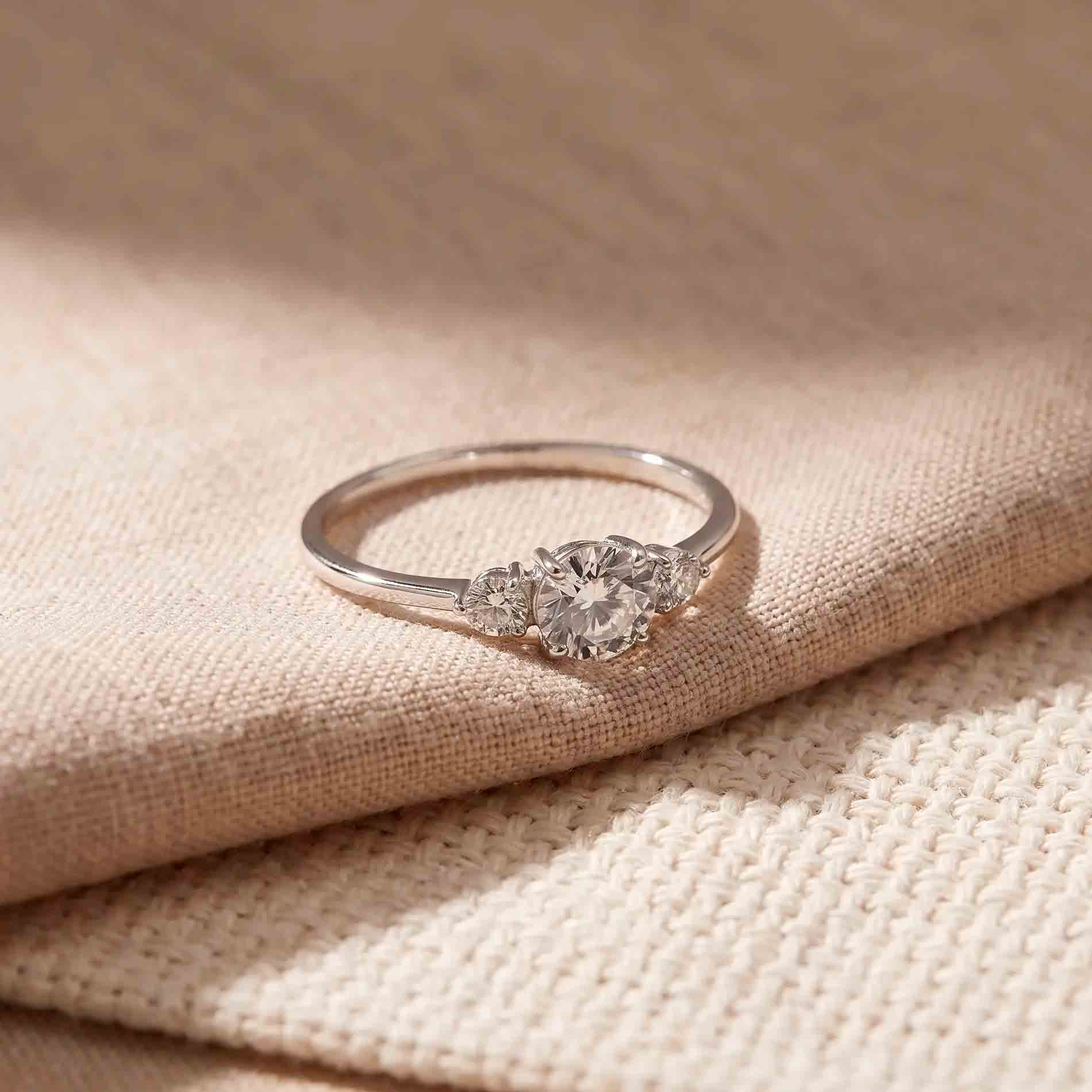Nina ring i sølv med rund klar zirkonia og to mindre zirkonia sten på tekstil