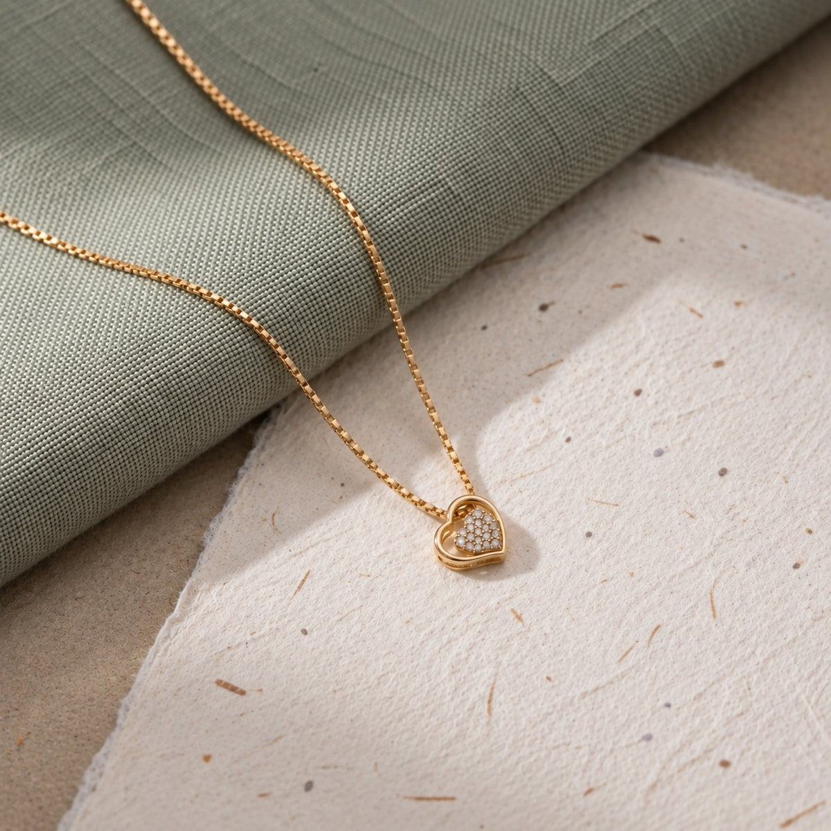 Open Heart vedhæng i guld med diamanter på grønt stof