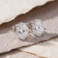 Oval-cut VIII Solitaire ørestikker i 925 sterlingsølv med klar zirkonia, vist som elegante sølvørestikker på stof