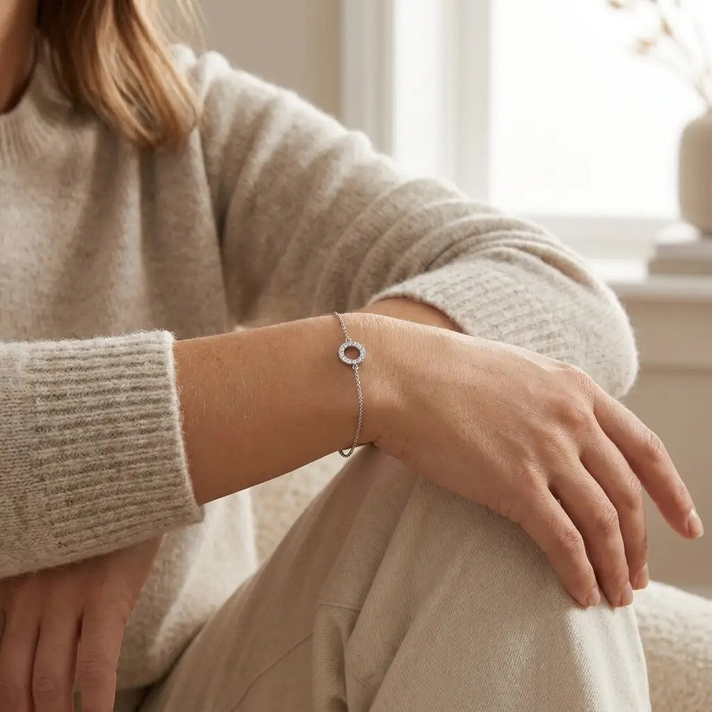 Kvinde i beige strik bærer Petite Halo armbånd i hvidguld med diamanter om håndleddet