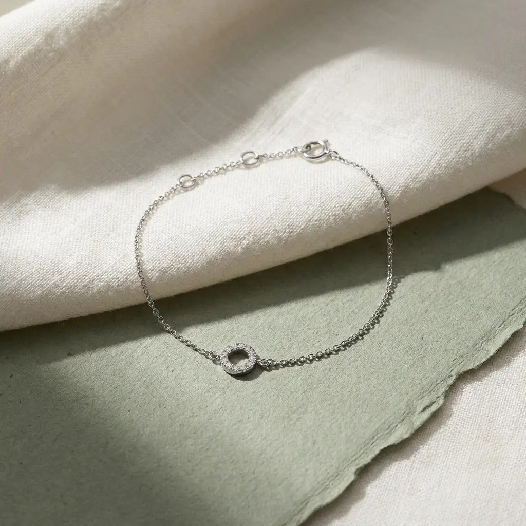 Petite Halo armbånd i hvidguld med diamanter på hvidt stof og grønt papir