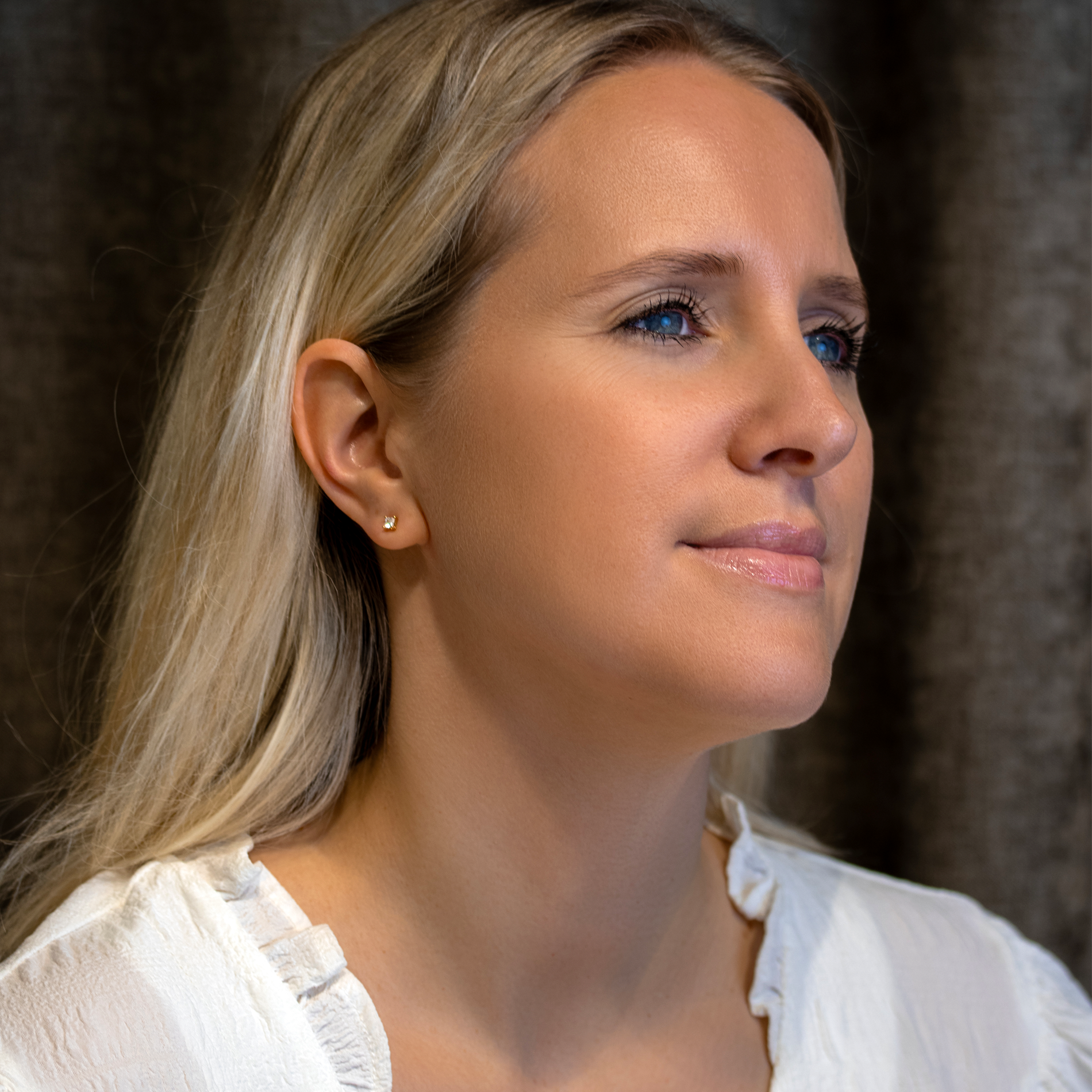 Model iført små princess-cut solitaire ørestikker i forgyldt sølv