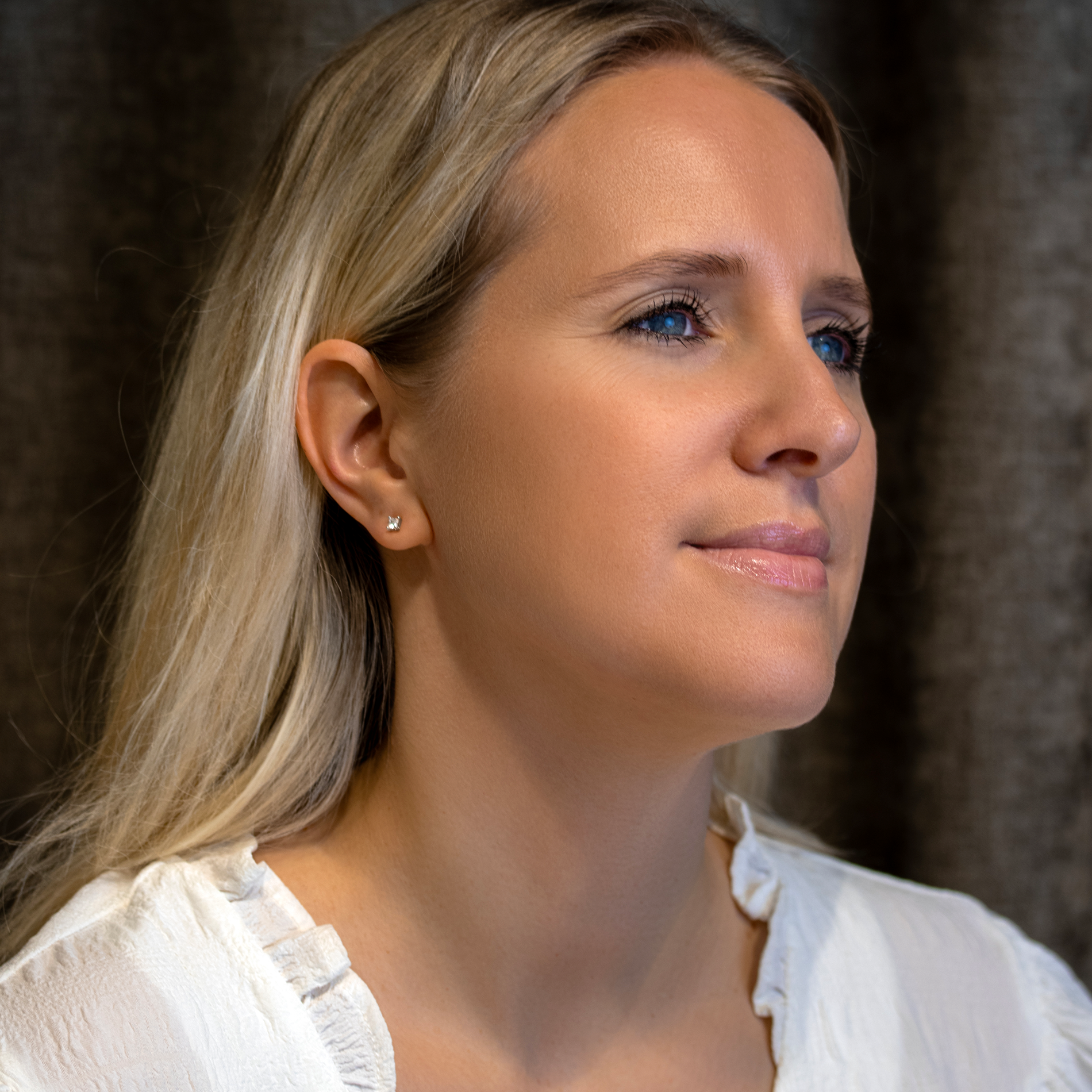 Model iført små princess-cut solitaire ørestikker i sterlingsølv