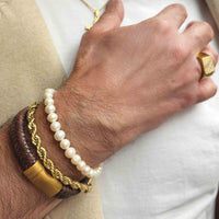 Scrouples armbånd med lyse ferskvandsperler på 6-7 mm vist på håndleddet sammen med andre armbånd.