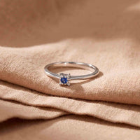 Wilma ring i 18 karat hvidguld med blå safir og diamanter, fotograferet på stof